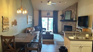 Ein geräumiges Wohnzimmer mit Essbereich, Kamin und einer Küche mit Spüle.