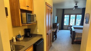 A compact kitchen with a microwave, coffee maker, and dishwasher. There is a dining area with a table and chairs, and a ceiling fan. - Studio 312 by Eagle Waters Resort (eagle river)