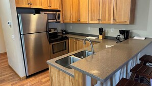 A modern kitchen with wooden cabinets, stainless steel appliances, a granite countertop, and a built-in sink.