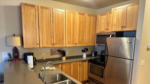 A kitchen with wooden cabinets, a stainless steel refrigerator, a toaster, and a coffee maker. - Spirit of the Northwoods (eagle river)