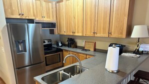 A modern kitchen with stainless steel appliances, wooden cabinets, a granite countertop, and a built-in sink. - CONDO 305/LOFT by Eagle Waters Resort (eagle river)