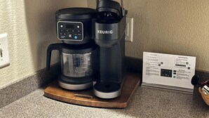 Een Keurig koffiezetapparaat op een houten dienblad, met een koffiekan en een waterreservoir.