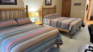A room with two beds, a wooden headboard, a nightstand with a lamp, and a door. - Studio 316 By Eagle Waters Resort (eagle river)