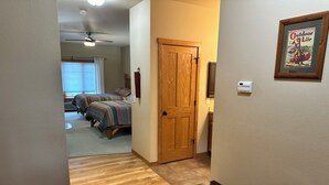 A hallway leading to a bedroom with a wooden door, a bench, and a framed magazine on the wall. - Studio 316 By Eagle Waters Resort (eagle river)