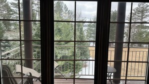 Vista a través de una ventana que muestra una terraza, sillas y una mesa.