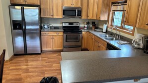 Una cocina con armarios de madera, electrodomésticos de acero inoxidable, microondas, tostadora y cafetera.