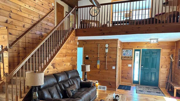 Un interior de madera con un sofá de cuero, una mesa de centro y una escalera.