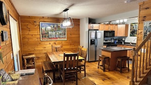 Una cocina acogedora de estilo cabaña, con pisos de madera, una mesa de comedor y un refrigerador.