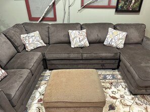 Relax in this inviting living space with a comfortable sofa, woven ottoman, and patterned rug.