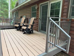 Une terrasse en bois, dotée de mobilier d’extérieur et d’une rambarde en métal.