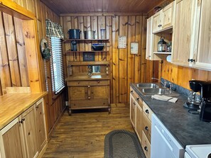 Una cocina con paneles de madera, un fregadero, una estufa y varios electrodomésticos.