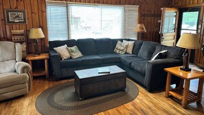 A cozy living room with a sectional sofa, a coffee table, and a wooden floor. - Cabin 2 by Eagle Waters Resort (eagle river)
