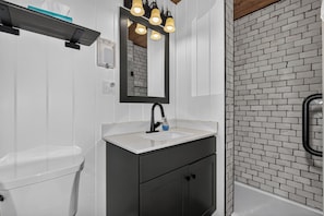 You'll appreciate the clean, modern design of this bathroom with its stylish tile shower, warm pendant lighting, and contemporary fixtures ready for your comfort.