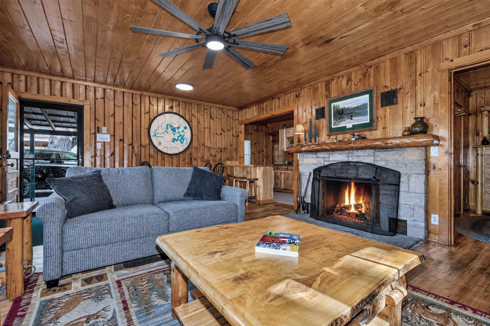 L’intérieur d’un chalet accueillant, avec une cheminée, des murs en bois, un canapé et une table à manger.