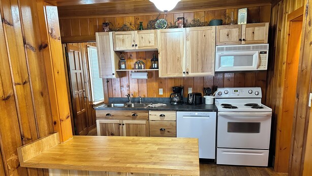 A wooden kitchen with a wooden table and stools, a sink, a stove, and cabinets. - Cabin 2 by Eagle Waters Resort (eagle river)