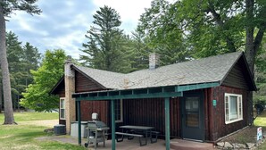 A rustic cabin with a covered patio, a grill, and picnic tables. - Cabin 2 by Eagle Waters Resort (eagle river)