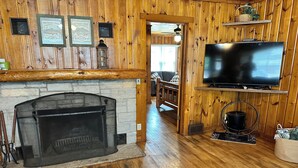 A cozy cabin interior with a stone fireplace, wooden walls, a television, and a rustic dining area. - Cabin 2 by Eagle Waters Resort (eagle river)