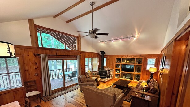 A cozy cabin interior with a fireplace, leather sofas, a TV, and a dining area with a wooden table and chairs. - Cabin 3 by Eagle Waters Resort (eagle river)
