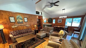 A cozy living room with a sofa, two armchairs, a coffee table, and a dining area with a table and chairs. - Cabin 3 by Eagle Waters Resort (eagle river)