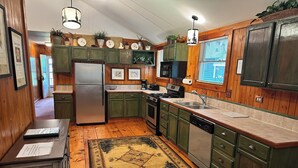A kitchen with wooden cabinets, a refrigerator, stove, sink, and a rug. - Cabin 3 by Eagle Waters Resort (eagle river)