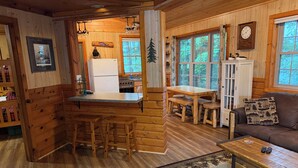 A wooden cabin interior with a kitchen, dining area, and living room. - Cabin 5 by Eagle Waters Resort (eagle river)