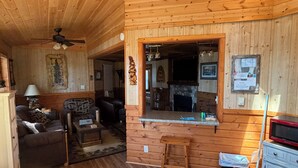 A log cabin interior with a living room, a fireplace, a kitchen area, and a dining table. - Cabin 5 by Eagle Waters Resort (eagle river)
