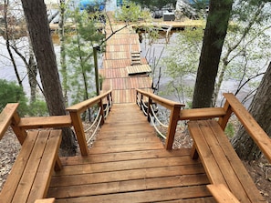 A wooden staircase leading to a wooden deck over water, surrounded by trees.