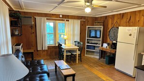 Una sala de estar acogedora con sofá, una mesa de comedor y una cocina equipada con refrigerador y televisor.