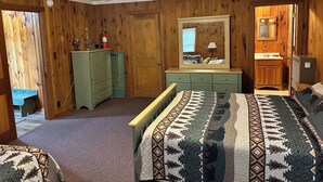 Un dormitorio de estilo cabaña con una cama, cómoda y ventilador de techo.