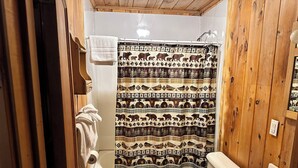 Un baño con detalles de madera, un inodoro, un lavabo y una cortina de ducha con motivos de animales.