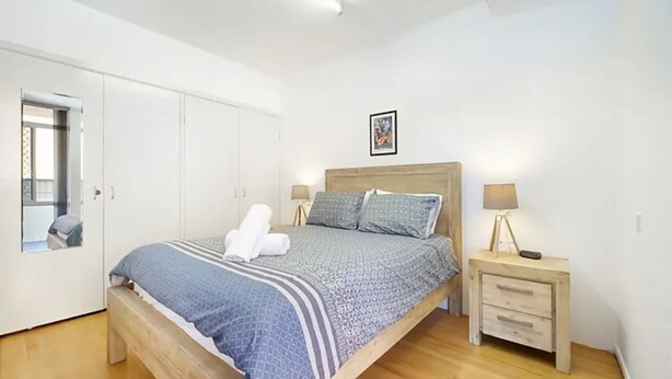 A bedroom with a bed, bedside tables, a wardrobe, and a framed picture on the wall.
