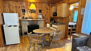 A cozy cabin interior with a stone fireplace, wooden dining table, and chairs. - Cabin 14A by Eagle Waters Resort (eagle river)