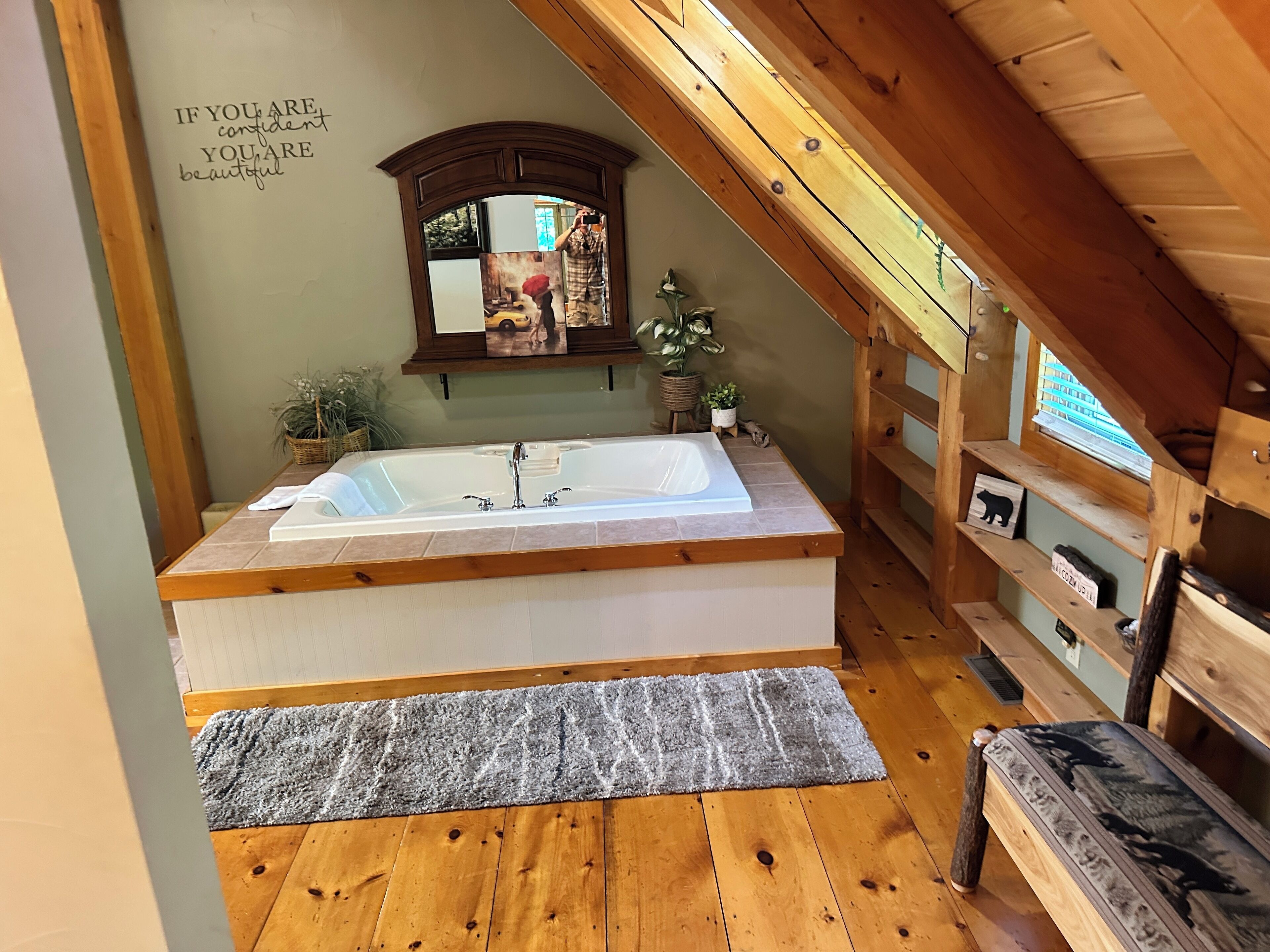 A bathroom with a wooden vanity, a large bathtub, and a mirror.