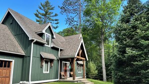 A two-story house with a green exterior and a stone pathway leading to the front door.