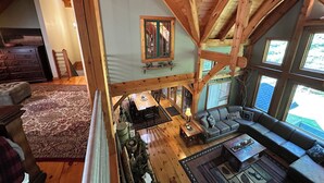 A spacious loft with high ceilings and exposed wooden beams. It features a cozy living area with a sofa, coffee table, and a dining table.