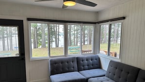 A room with a grey sectional sofa, large windows, a ceiling fan, and a view of an outdoor deck with a picnic table. - 2-2 4-Plex by Eagle Waters Resort (eagle river)
