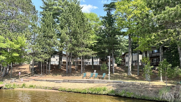 A lakeside view with a row of cabins and a picnic area with chairs and tables. - 2-2 4-Plex by Eagle Waters Resort (eagle river)