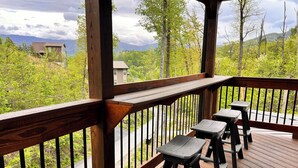 A wooden deck with outdoor seating and a view of a mountainous landscape.