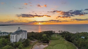 A coastal hotel with a view of the sunset over the water, surrounded by lush greenery and a golf course. - Studio Condo in Luxe Sandestin Resort w/ Balcony, Pool, + Walk to Baytowne Wharf (Miramar Beach)