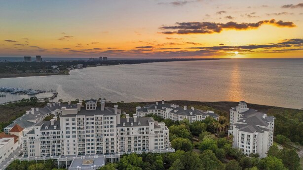 A large, multi-story hotel with a central courtyard, located near a waterfront with boats docked. - Studio Condo in Luxe Sandestin Resort w/ Balcony, Pool, + Walk to Baytowne Wharf (Miramar Beach)