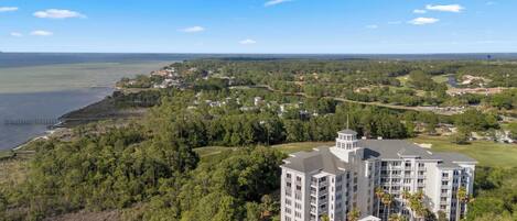 A large resort with multiple buildings, including a prominent tower, surrounded by lush greenery and a body of water.