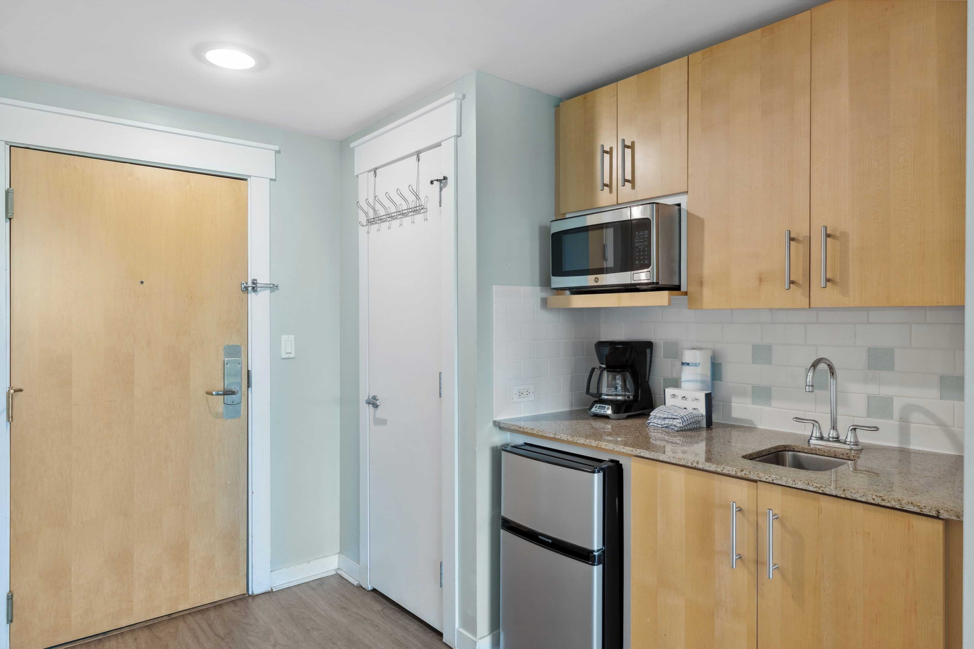 Une cuisine compacte avec des meubles en bois, un réfrigérateur en acier inoxydable, un four à micro-ondes et un évier.