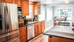 Une cuisine moderne avec des meubles en bois, des appareils électroménagers en acier inoxydable et un grand îlot central.
