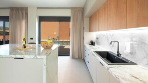 A modern kitchen with a marble countertop, a black sink, wooden cabinets, and a view of a pool.
