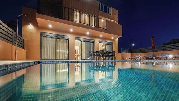 A modern two-story building with a swimming pool, outdoor seating, and a balcony.
