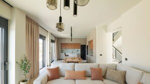 A modern living room with a sectional sofa, a dining area, and a kitchen in the background.