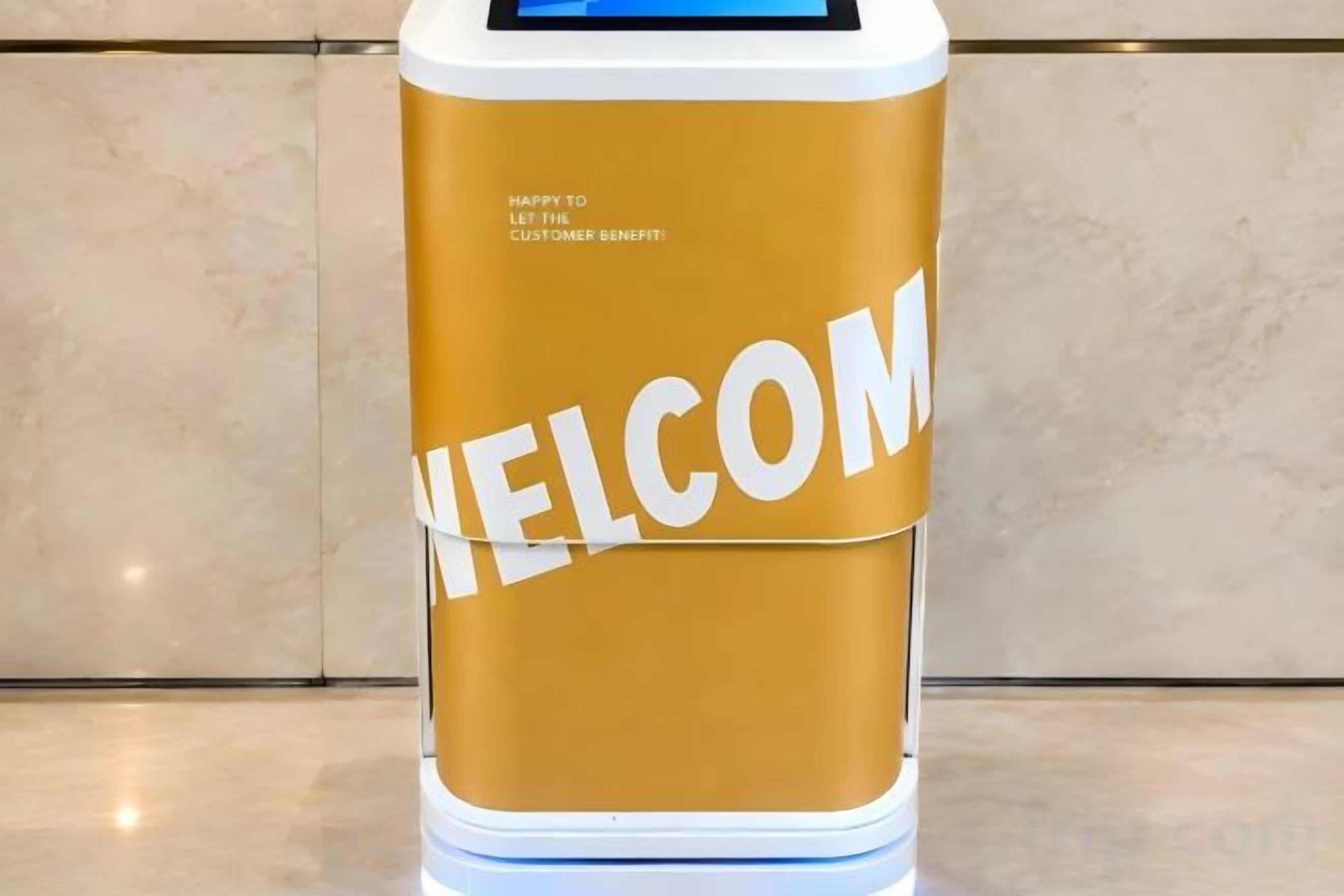 Un quiosco cilíndrico con una pantalla digital y la palabra 'WELCOME' mostrada en grande.