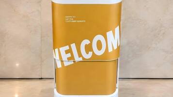 Un quiosco cilíndrico con una pantalla digital y la palabra 'WELCOME' mostrada en grande.