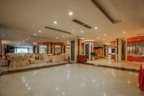 Amplio espacio interior con mesas, sillas, un atril y una barra con productos a la vista.