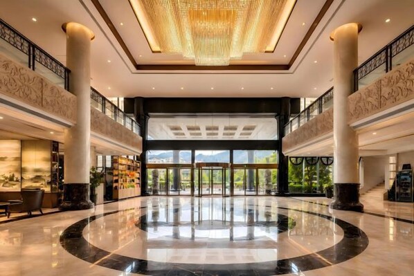 A spacious lobby with a high ceiling, large columns, and a grand chandelier.